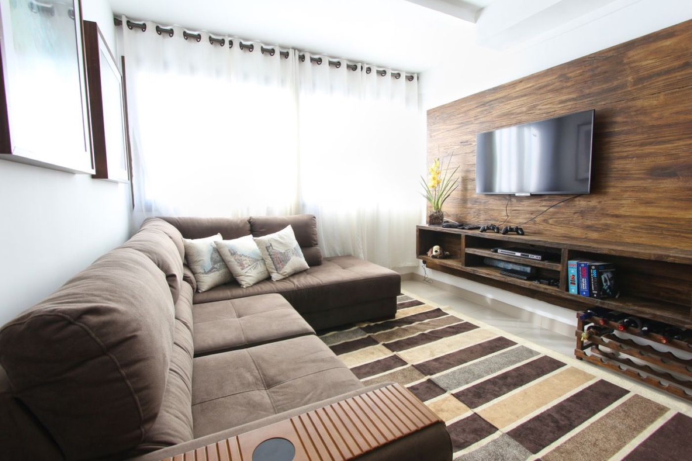 A finished lower-level family room with a sectional and a wood accent wall.